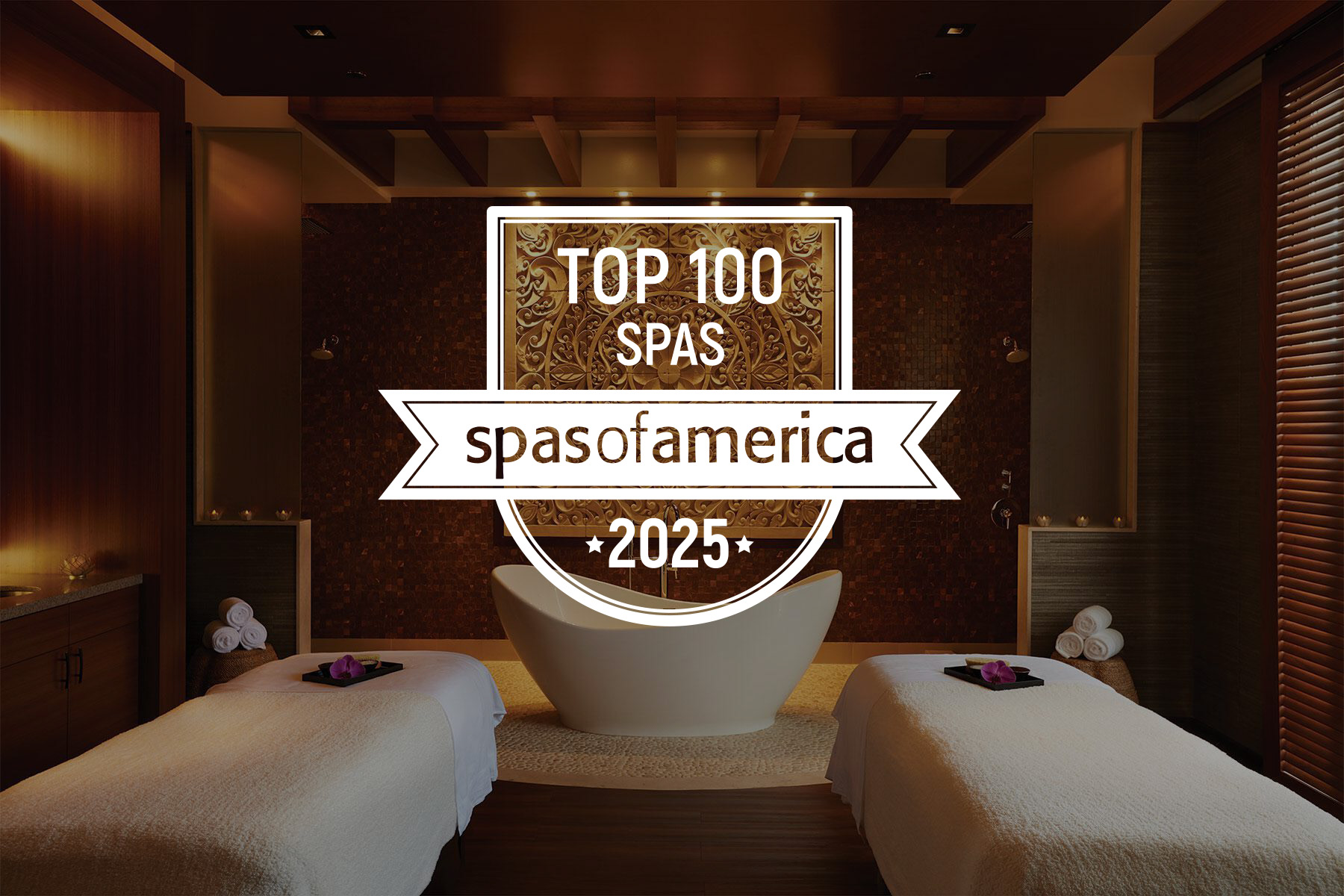 Luxury spa room with a bathtub between two massage tables, dim lighting, and "Top 100 Spas of America 2025" badge in the center.